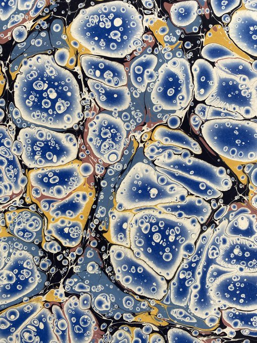 An abstract marbled artwork featuring organic blue, white, yellow, and black shapes with bubble-like textures throughout the composition.