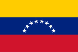 The image features a flag with the colors red, yellow, blue, and white. The flag has a unique design that resembles an arch or a bow, which adds visual interest to the scene. The background of the image is gray, providing a neutral backdrop for the vibrant colors of the flag. In the corner of the image, there's a caption that reads "@elsultanbitcoin points out that an electricity reform approved in Venezuela could open the door to Bitcoin mining." This statement connects the flag design with the ongoing developments in Venezuela and Bitcoin mining.