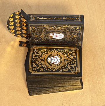 A deck of ornate black and gold 'Embossed Gold Edition' playing cards featuring decorative cameos, stacked on a table.
