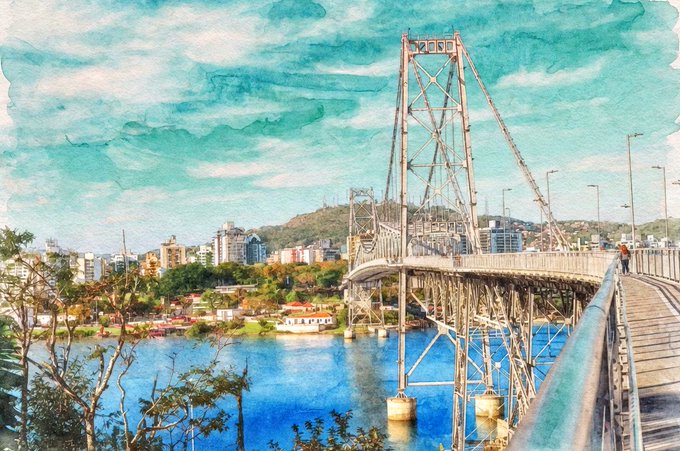 The image features an aerial view of a bridge over water, which appears to be made of metal. The bridge spans across a river or lake, connecting two areas separated by the water body. There are also trees visible near the bridge, adding to the natural beauty of the scene. The photo is described as being in color and possibly a painting, suggesting that it might have been taken during the day under good weather conditions.