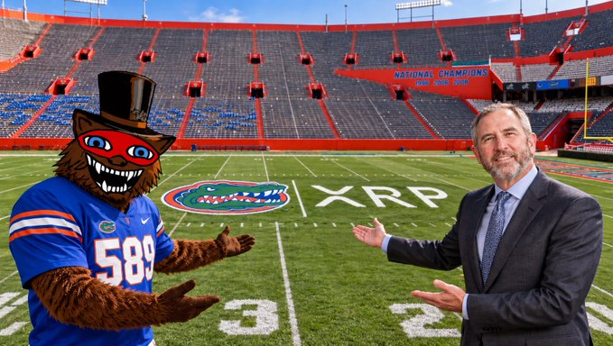 University of Florida mascot Albert the Alligator, wearing a top hat and jersey #589, stands alongside a man in a suit on Ben Hill Griffin Stadium's field, gesturing toward the newly painted XRP logo and Florida Gators logo at the 25-yard lines, promoting Ripple's multi-year sponsorship deal that will debut before a national TV audience this Saturday.