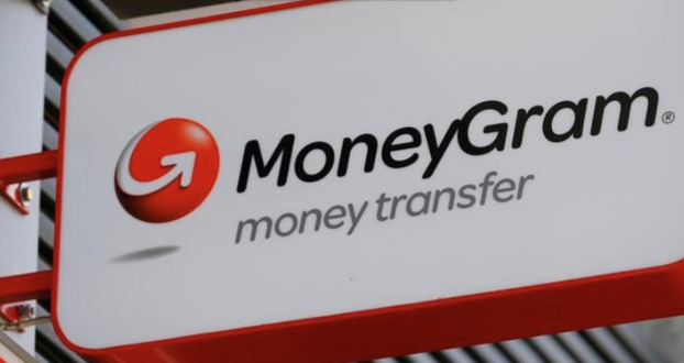 A close-up of the MoneyGram money transfer sign displaying the company's logo with a red sphere and curved arrow design on a white and red background.
