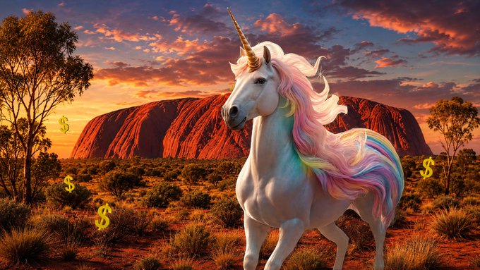 A fantasy image of a white unicorn with a flowing rainbow mane standing in an Australian outback landscape with Uluru in the background, surrounded by floating yellow dollar signs.