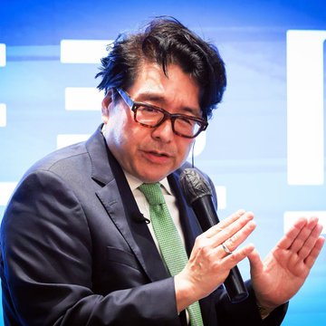 A bespectacled man in a dark suit and green tie speaks into a microphone while gesturing with his hands, likely discussing BitMine's latest Ethereum acquisition. The accompanying text notes that BitMine has purchased another 15,112 ETH, bringing its total holdings to over 6 million ETH valued at approximately $16.4 billion—roughly 4.9% of the entire ETH supply—suggesting the company shows no signs of slowing its accumulation.