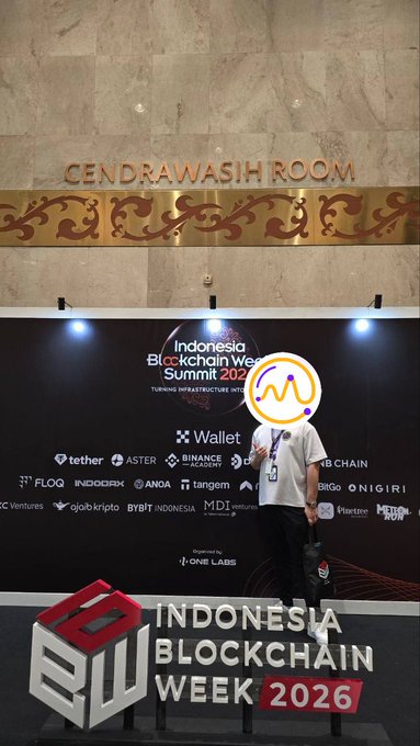 A person stands in front of an 'Indonesia Blockchain Week Summit 2026' banner at the Cendrawasih Room, with various crypto sponsors like Tether, BNB Chain, and Wallet visible.