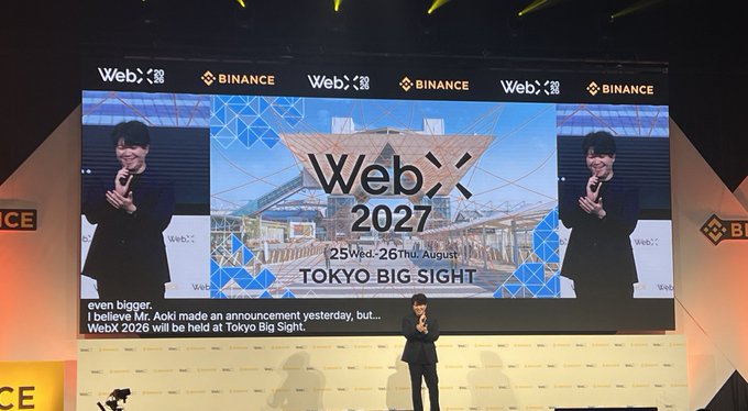 A speaker delivers closing remarks at WebX 2026, standing on stage before a large screen announcing "WebX 2027," scheduled for August 25-26, 2027 at Tokyo Big Sight, with Binance and WebX branding visible in the backdrop, matching the post's announcement of the next event featuring 1.8 times the venue space.