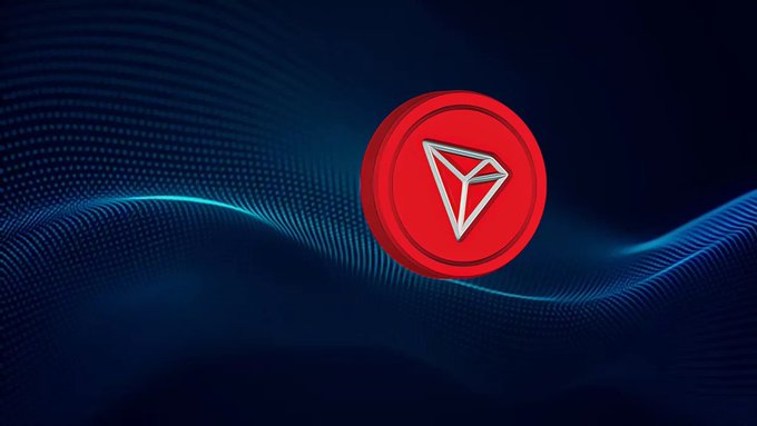A red Tron (TRX) cryptocurrency coin featuring the white TRX logo emblem, displayed against a dark blue background with flowing wavy digital particle patterns.
