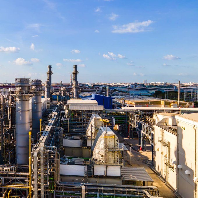 An aerial view of an industrial refinery complex with tall smokestacks, processing units, and piping under a partly cloudy sky. The image visually reinforces the article's focus on energy and commodities markets, particularly natural gas, by showcasing the kind of large-scale oil and gas infrastructure tied to the sectors being discussed.