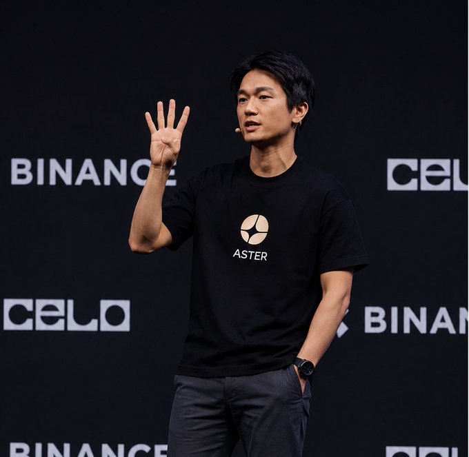 A man in a black "ASTER" t-shirt gestures with his hand raised while speaking on a stage, with "BINANCE" and "CELO" logos visible on the backdrop behind him. The image visually ties to the post's message about $ASTER staking milestones, presenting the speaker as the figure behind the impressive 400M+ staked achievement.