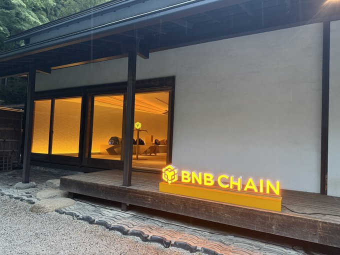 A traditional Japanese-style building with illuminated interior, featuring an acrylic sign displaying the "BNB CHAIN" logo and name placed on the wooden porch steps—added humorously by the poster to capture the atmosphere, as they joked about having to place the sign themselves since it had fallen down.