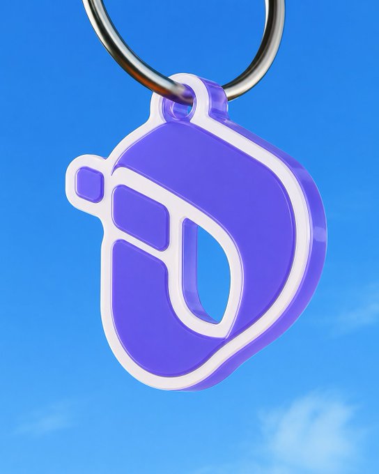 A purple and white plastic keychain shaped like a stylized letter 'D' or helmet hangs against a blue sky background.