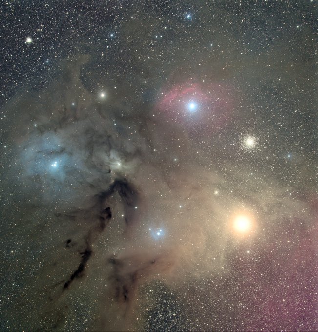 A stunning astrophotography image showing a colorful nebula with bright stars in shades of blue, pink, and orange against a dark sky.