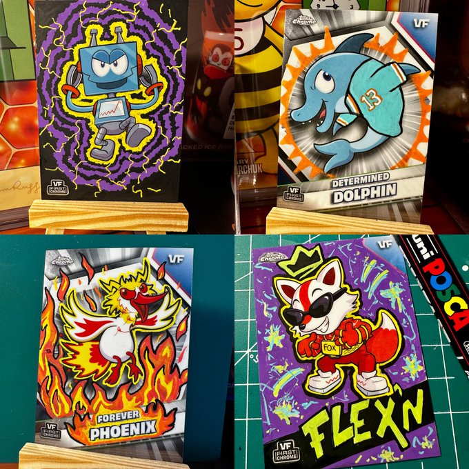 Four colorful animated-style trading cards displayed: a purple 'Robot', a blue 'Determined Dolphin', a fiery 'Forever Phoenix', and a purple 'Flex' dog character wearing sunglasses.
