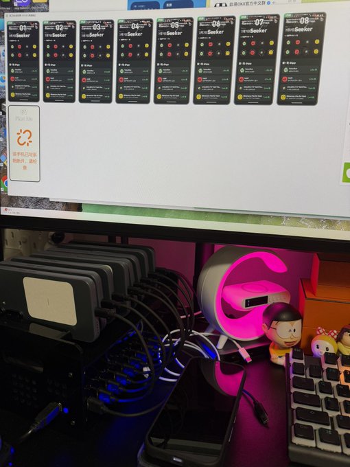 A monitor displays eight "01-08 Seeker" digital collectible cards from a Solana Phone Seeker ($SKR) Summer event, with the first week's set fully collected. Below the screen, a charging dock holds multiple smartphones next to a pink-lit figurine and keyboard, illustrating the daily check-in process needed to earn the week 1 NFT set.
