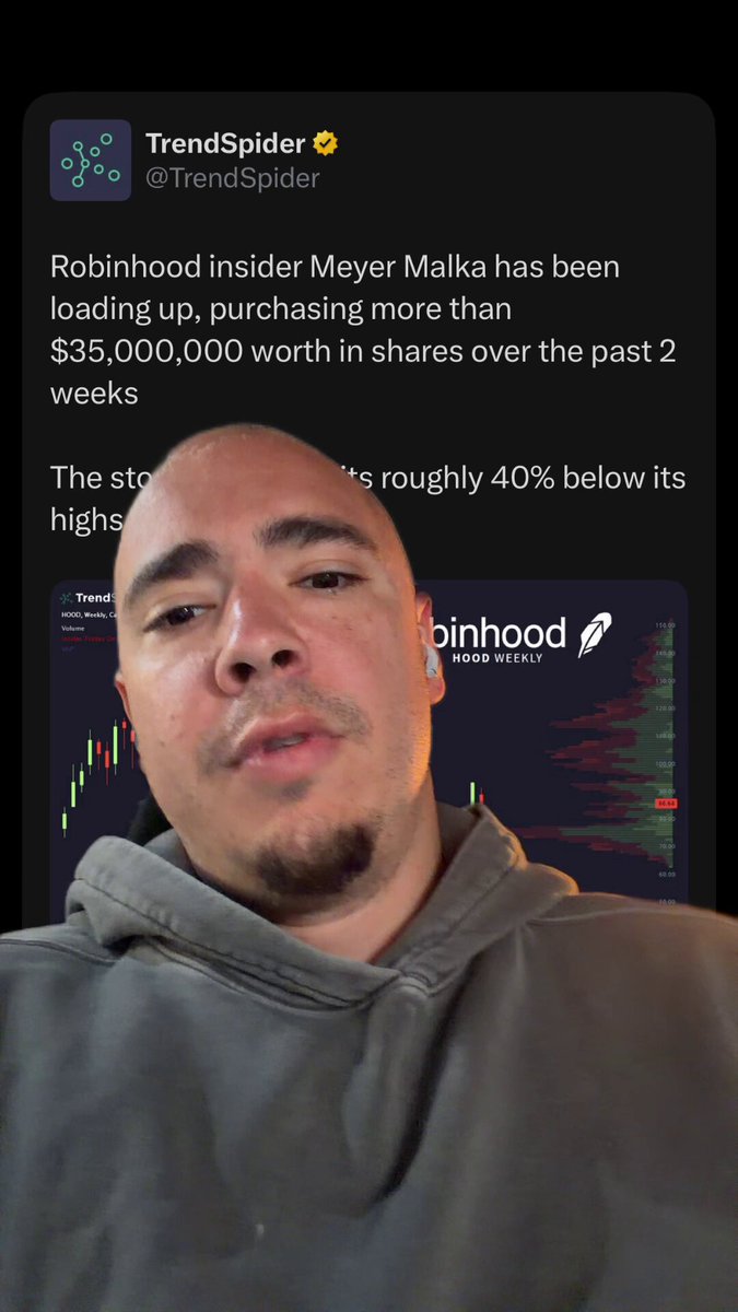 The image features a man sitting in front of his phone with a serious expression, staring at the screen as if he's reading or watching something important. He has a gray sweatshirt on, giving off a casual vibe. On the mobile device screen, there is a Twitter account that displays an article about Robinhood and bitcoin, specifically mentioning Michael Saylor. The image also includes text elements such as "TrendSpider" and "Twitter Insider Meyer Malika", suggesting some connection to these platforms or the topic at hand.
