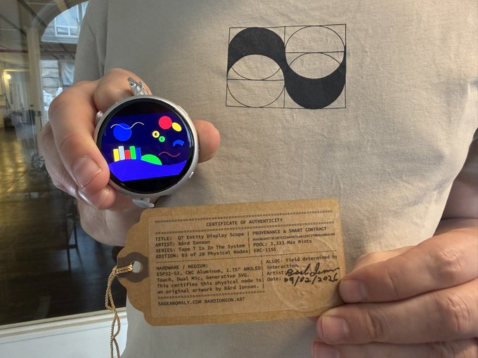 A person in a gray geometric-print t-shirt holds a circular smart display showing colorful artwork alongside a 'Certificate of Authenticity' tag for 'Pope.T In The System' by Bird Joonson.