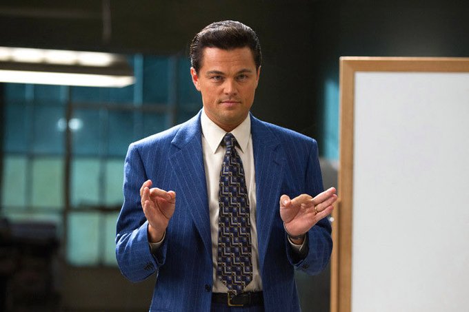 A man in a blue pinstripe suit with a patterned tie stands in a modern office setting, his hands raised in a gesture as if explaining a concept. The post's phrase "The liquidity is programmable" suggests the image evokes the famous "money gif" scene, symbolizing the fluid, controllable nature of programmable financial systems.