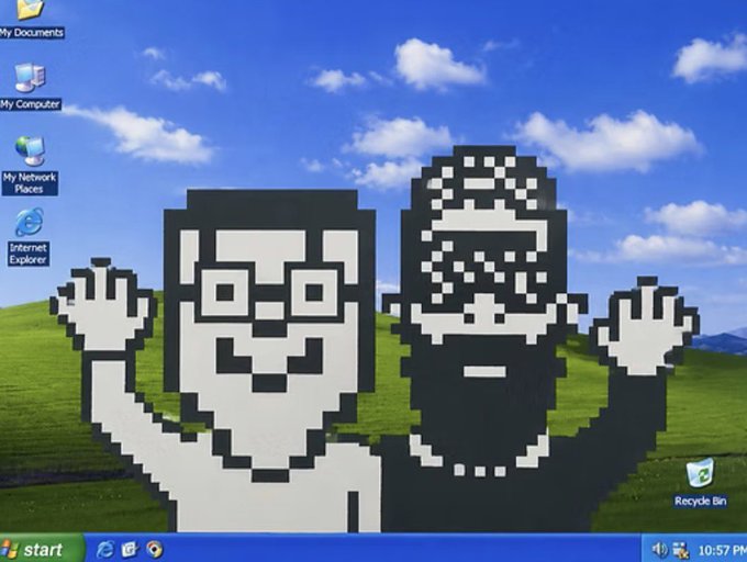 A pixel art illustration of two figures superimposed over the classic Windows XP 'Bliss' desktop wallpaper background, featuring desktop icons for My Documents, My Computer, My Network Places, and Internet Explorer.