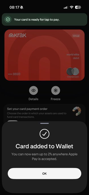 An iPhone screen showing a Kraken World Elite debit Mastercard successfully added to Apple Wallet, displaying 'Card added to Wallet' confirmation with up to 2% earnings where Apple Pay is accepted.