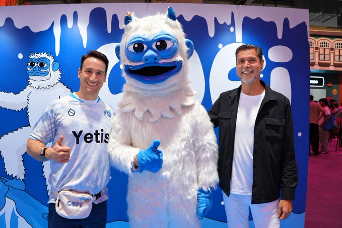 Two men pose with a white Yeti mascot in front of a branded backdrop featuring the "Yetis" logo, with the man on the left giving a thumbs-up and wearing a jersey displaying "Yetis" and "Caopa" text. The mascot's friendly, promotional appearance suggests a meet-and-greet or sponsorship event, fitting the post's tone of celebrating a new connection.