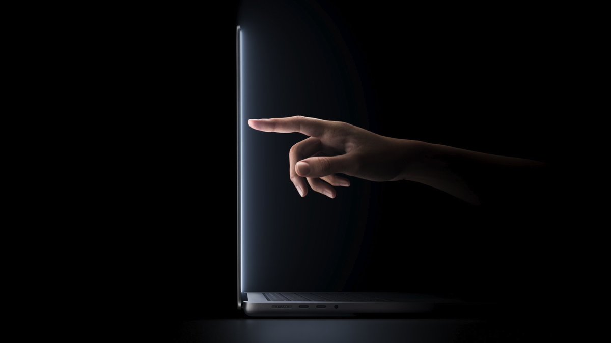 A hand reaches from the right to touch the glowing edge of a thin open laptop against a black background.