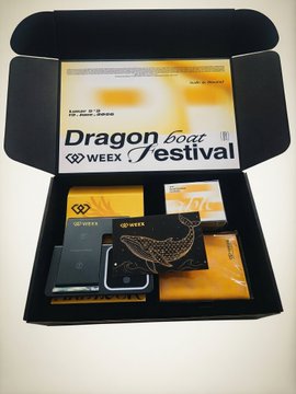 The image features a black box containing various items, including a cell phone, a wallet, and some other accessories. The box also has a label that reads "Dragon Boat Festival" and "WEEX", indicating its purpose or brand. The presence of these items suggests that they are related to the Dragon Boat Festival, which is an event celebrating Chinese culture and tradition.