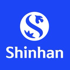 The image shows the Shinhan logo, featuring a stylized white "S" emblem within a larger white circle on a blue background, with "Shinhan" written in bold white text below. This represents the South Korean financial conglomerate that recently partnered with Visa to develop a stablecoin-based financial infrastructure.