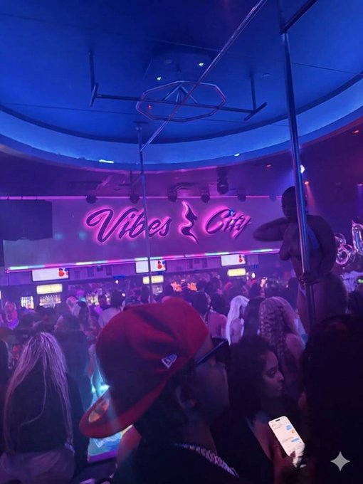 A crowded nightclub scene illuminated by blue and pink neon lights, featuring a neon sign that reads "Vibes City" with a dancer on a pole in the background.