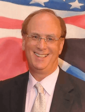A man in a suit and glasses is smiling in front of an American flag backdrop, with the context of nearly $1 billion flowing into U.S. spot bitcoin ETFs in a single day, marking a 2026 record as Wall Street resumes BTC accumulation.