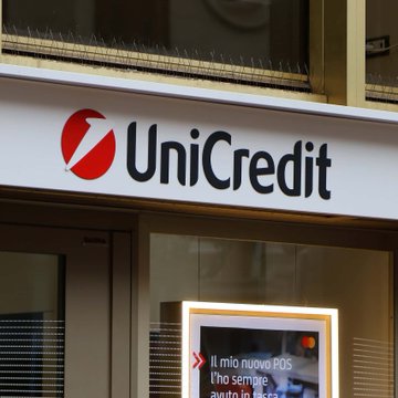 The image shows a UniCredit bank storefront, featuring the company's red logo and name on the signage above the entrance, with a promotional poster mentioning "Il mio nuovo POS" visible in the window. This relates to the news as UniCredit, Italy's second-largest bank, is reportedly considering expanding into cryptocurrency custody and brokerage services.