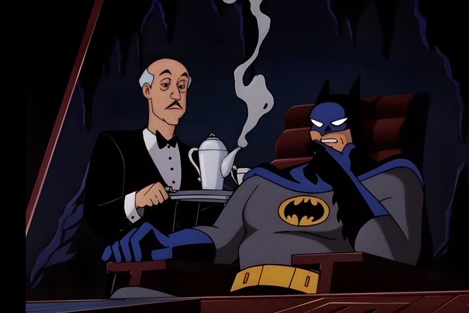 An animated scene showing Batman sitting in a chair while Alfred, his butler, serves him tea in what appears to be the Batcave.