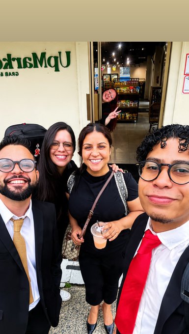 A group of four friends pose for a selfie outside a bar with "Uptown Six Bar" partially visible on the wall behind them.