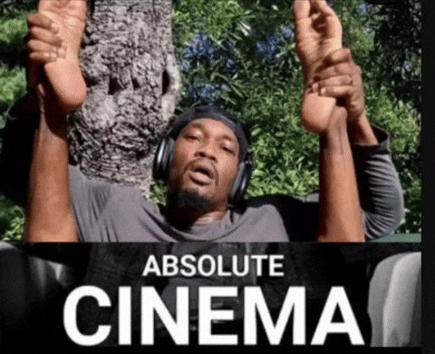 The image features a man with his arms raised up, wearing headphones and holding onto tree branches as if he's hanging from them. The caption below the photo reads "Absolute Cinema", which seems to be a reference to an old movie or TV show.