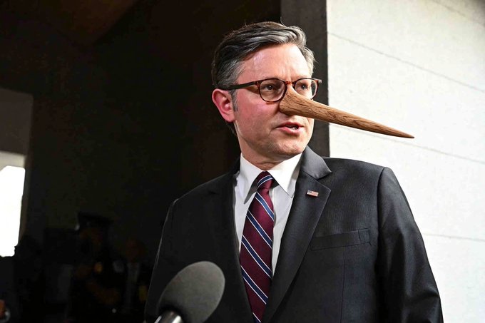A man in a suit and tie with glasses stands at a microphone with a digitally added long Pinocchio-like nose, suggesting a humorous edit about lying.