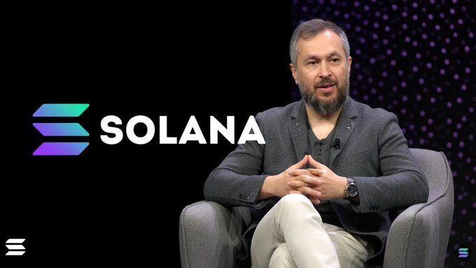 Anatoly Yakovenko, co-founder of Solana (SOL), sits during an interview with the Solana logo displayed beside him, discussing his vision of finance as one giant state machine with atomically accessible markets.