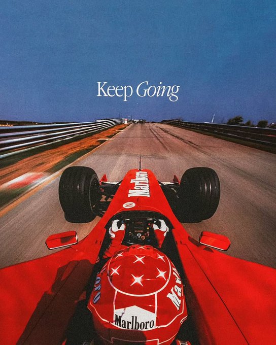 A point-of-view shot from inside a red Formula 1 race car speeding down an empty track, featuring the iconic "Marlboro" sponsorship logo on the driver's helmet and the inspirational text "Keep Going" overlaid against a clear blue sky. The image's racing spirit and motivational message tie into the post's theme of perseverance—encouraging holders to keep racing through the volatility while staying grounded, just as a driver must occasionally step away from the throttle to "touch grass."