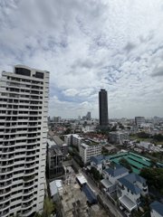 A view from a high-rise building overlooking a sprawling cityscape under a cloudy sky, with a prominent dark skyscraper and numerous residential and commercial buildings stretching to the horizon, capturing the urban setting that frames a day of hackathon wins, networking, and coworking milestones.