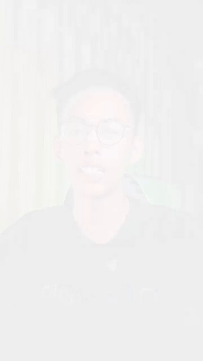 The image features a young man wearing glasses, with his face partially obscured by a white wall or screen behind him. The background appears to be a light brown color. The main focus of the image is the person's face, which is the central element in this composition.