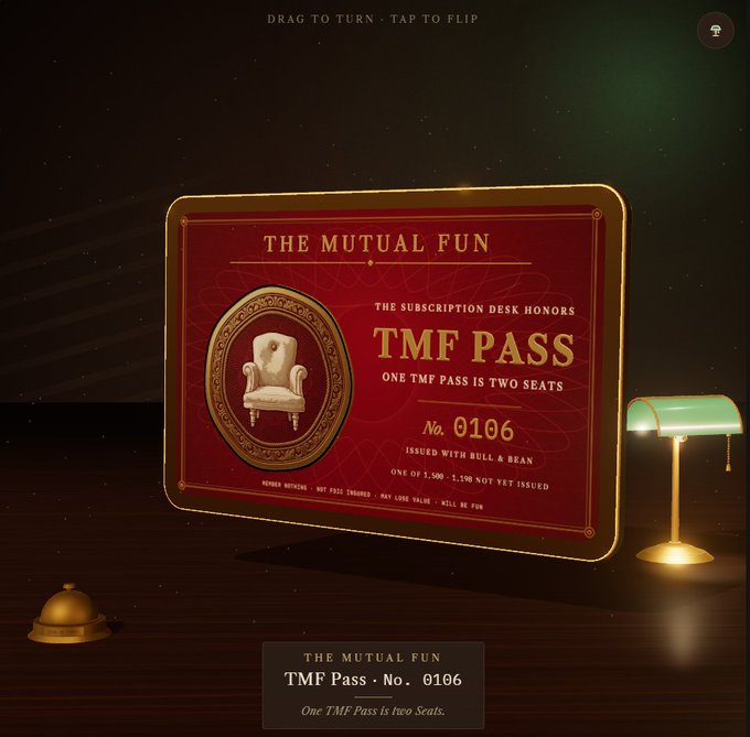 A digital rendering of a red 'THE MUTUAL FUN TMF PASS No. 0106' with gold borders, displayed on a dark wooden desk beside a green-shaded banker's lamp and a service bell, with the text 'One TMF Pass is two Seats' below.