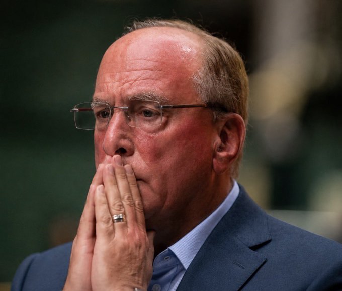 BlackRock CEO Larry Fink photographed in a pensive pose with his hands pressed together near his face, visually accompanying news of his firm and Fidelity offloading more than $60 million in Bitcoin holdings.