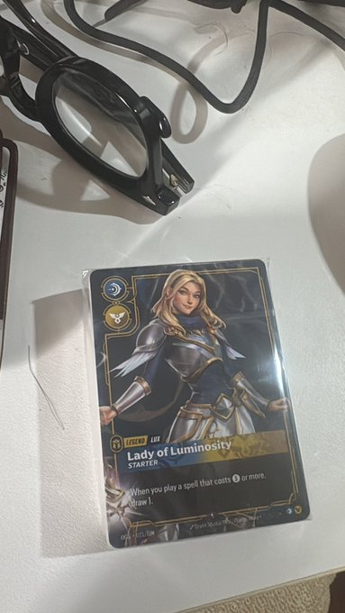 A "Lady of Luminosity" STARTER trading card from the Legends Lux archetype sitting on a white surface next to a pair of black glasses.