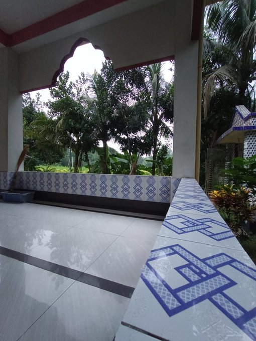 A shaded porch with blue geometric tilework overlooks a lush tropical garden, offering a calm, forward-looking view that complements the post's message about building for the future with @QuipNetwork.