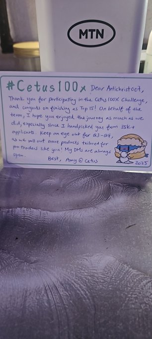 A handwritten thank-you note on white paper reads '#Cetus100x Dear Antichristcat, Thank you for participating in the Cetus 100X challenge...' and is signed 'Best, Amy @ Cetus 2023' with an MTN logo visible above.