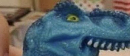 A close-up of a blue dinosaur figurine with sharp teeth and a green eye. The image humorously accompanies a post about bouncing the Tether (USDT) chain back up from its bottom, using the fierce toy dinosaur as a playful visual metaphor for snapping back.