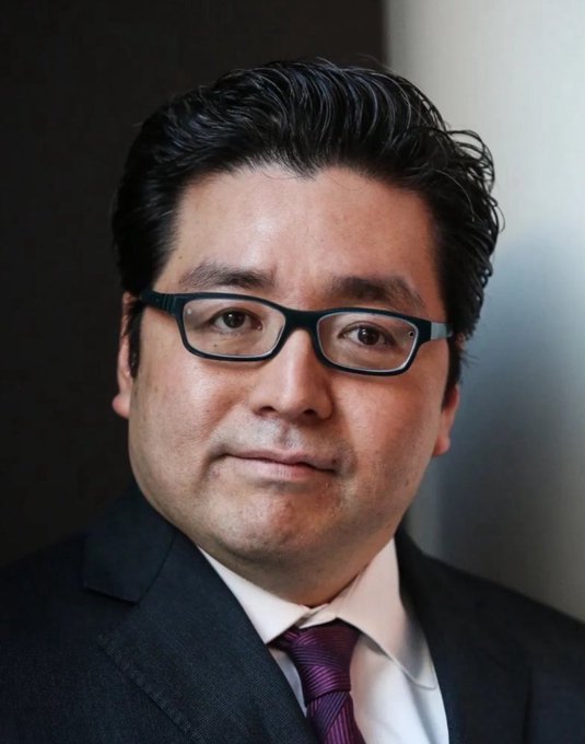 A portrait photo of a middle-aged East Asian man wearing glasses, a dark suit, white shirt, and purple tie.