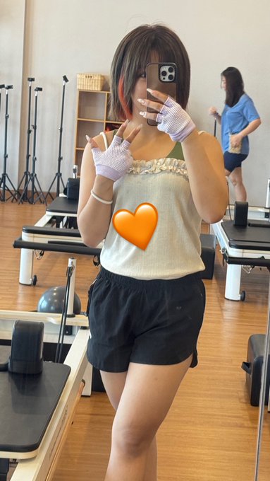 A woman takes a mirror selfie in a pilates studio after her morning workout, making peace signs while wearing workout gloves and shorts. The post highlights her healthy morning routine, combining her pilates session at 8 AM in Bali with breakfast plans, after attending CoinfestAsia and focusing on trading with MEXC.