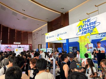 A crowded indoor event hall features a large sign reading 'THE FUTURE STARTS HERE.' along with 'Salesforce' and 'Nova Labs' branding, filled with attendees at booths.