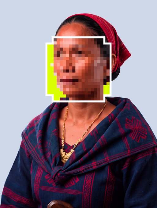 A portrait of an older woman wearing a red headscarf and a dark blue patterned shawl with a gold pendant necklace, with her face intentionally pixelated.