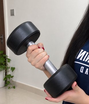 A woman holds a black dumbbell in one hand, illustrating her Day 3/21 fitness challenge post about showing up daily and staying consistent. The caption references @injective and the hashtag #InjectiveFit21; partially visible shirt text reads “NI…” and “DA.”