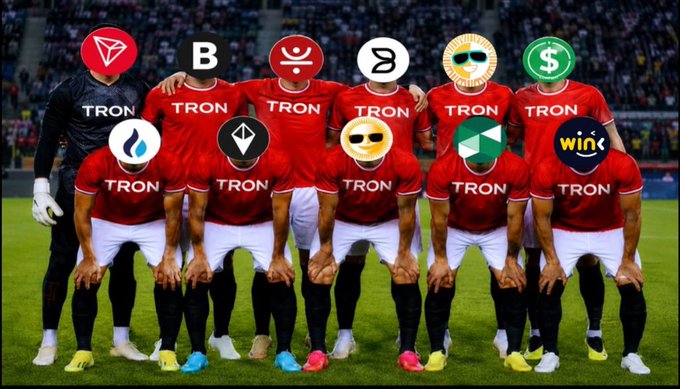 The image features a group of soccer players posing together with their team jerseys on, showcasing their unity as a team. The players are wearing red shirts that have various logos and emojis printed on them, including "TRON", "B", "TRON", "B", "TRON", "B", "TRON", "B", "TRON", "B", "TRON", and "TRON". These team members appear to be supporting a soccer team named "@Justinsuntron" or possibly a player from the same team. The background of the image is a stadium filled with spectators, emphasizing the importance of their support for the team.